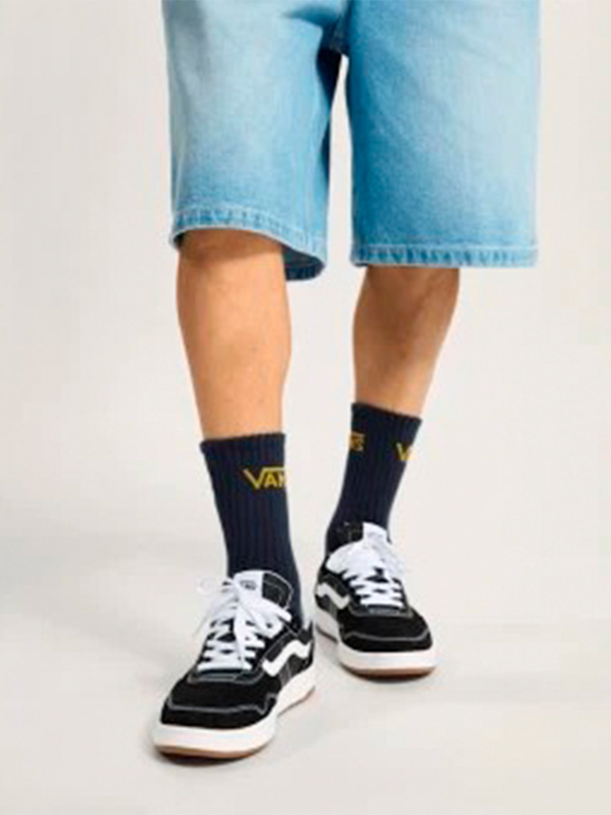 Persona con shorts de mezclilla y zapatillas Vans Cruze 3.0 negras