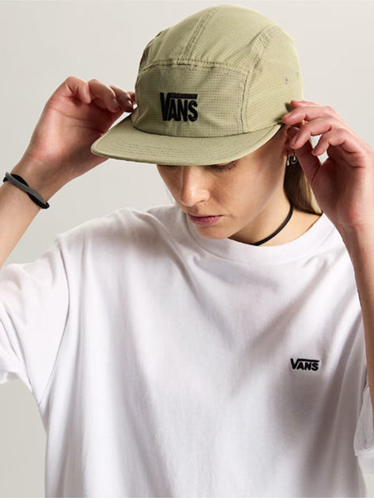 Mujer con el jockey camper Vans verde y polera blanca