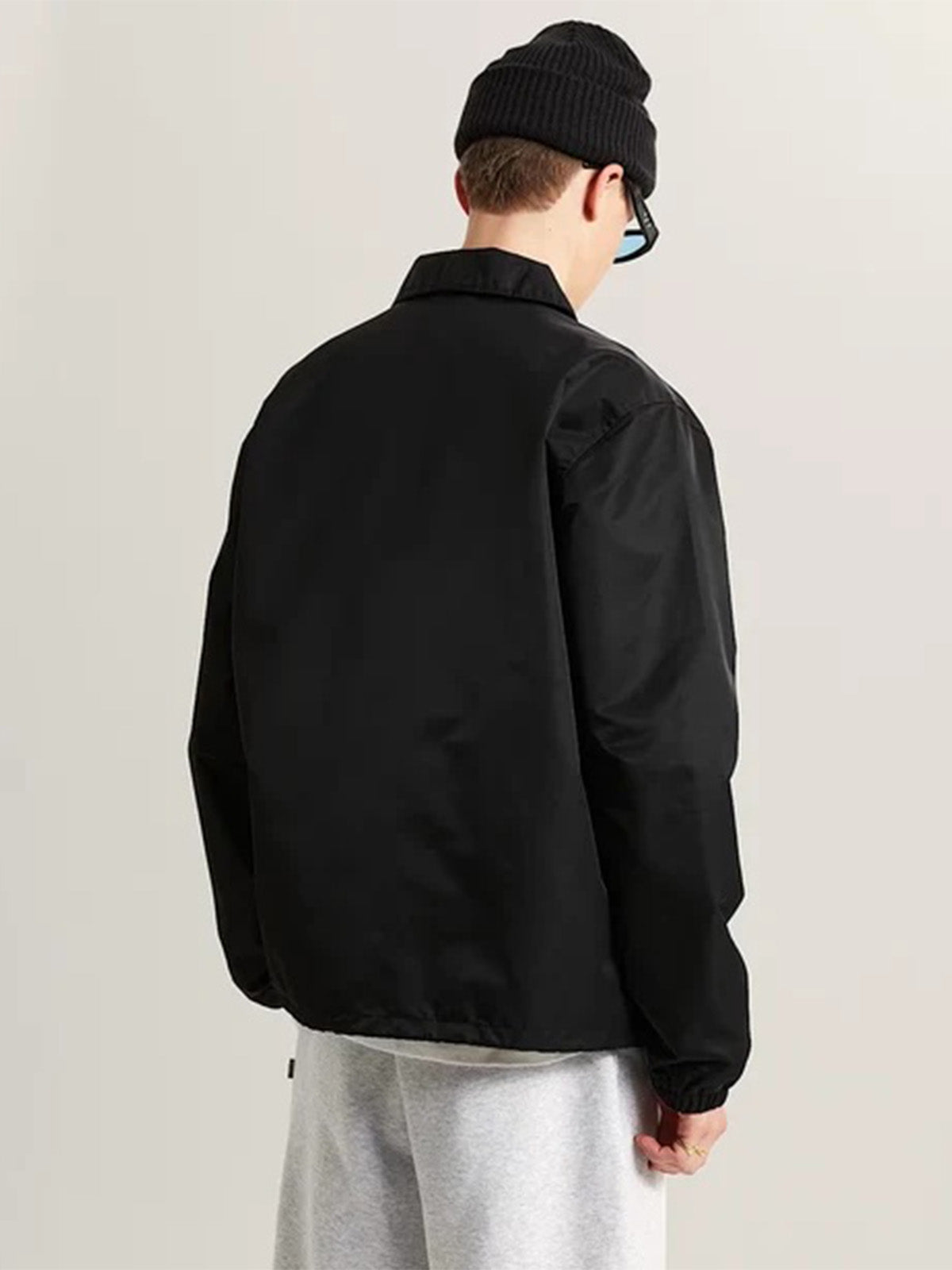 Hombre con la chaqueta coach Vans negra, vista de espalda
